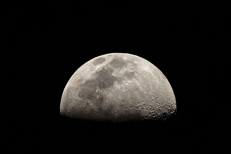 A photo taken of the dark side of the moon with nothing but black space in the background. 